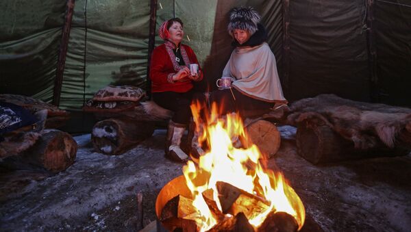 Женщины у костра в чуме в частном хозяйстве саамов в поселке при железнодорожной станции Лопарская в Кольском районе Мурманской области