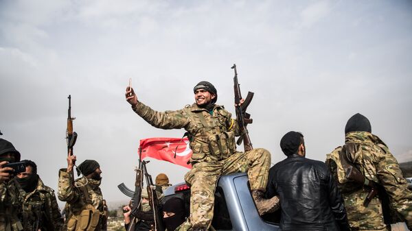 Боец сирийской оппозиции фоторафирует колонну турецких солдат около сирийской границы. Архивное фото
