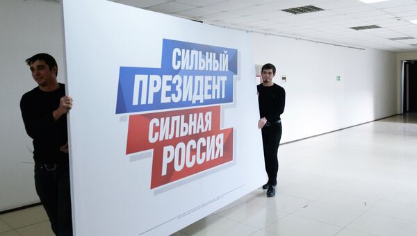 Рабочие несут плакат в избирательный штаб действующего президента РФ Владимира Путина в Грозном