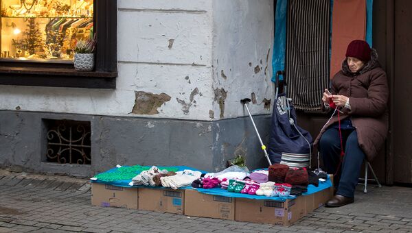 Женщина продает вязаные вещи в старом городе в Вильнюсе