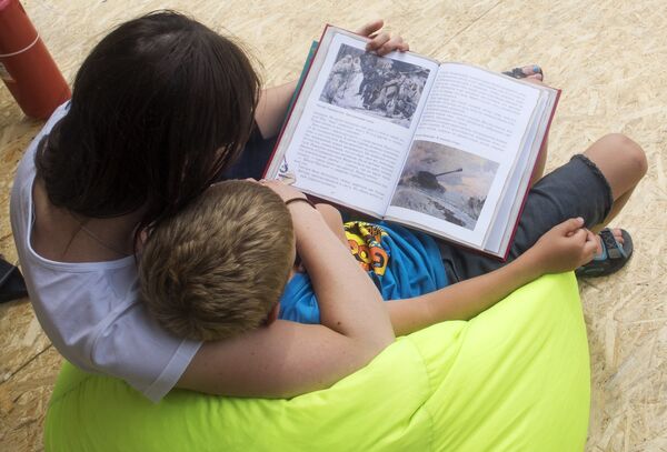Женщина и ребенок читают книгу на одной из площадок Московского фестиваля Книги России на Красной площади Женщина и ребенок читают книгу на одной из площадок Московского фестиваля Книги России на Красной площади