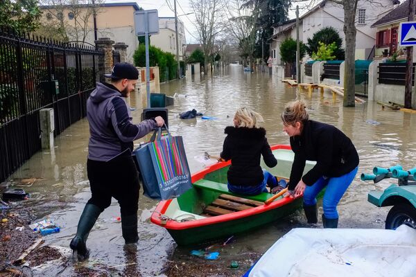 Местные жители переправляются на лодке на одной из затопленной улице в Париже, из-за прошедших ливневых дождей