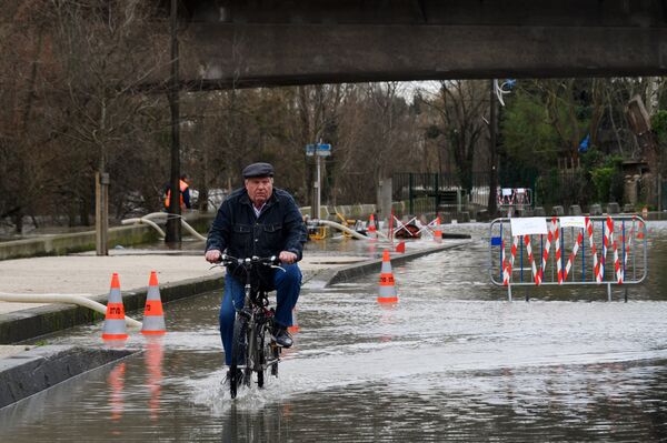 Местный житель едет на велосипеде по одной из затопленных улиц в Париже, из-за прошедших ливневых дождей.