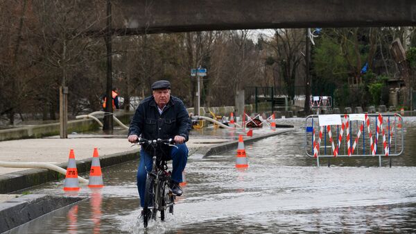 Местный житель едет на велосипеде по одной из затопленных улиц в Париже, из-за прошедших ливневых дождей. Архивное фото