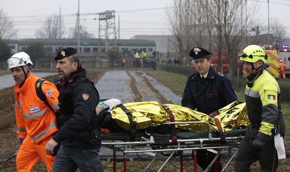 Спасатели и полицейские везут пострадавшего на месте крушения поезда на окраине Милана, Италия. 25 января 2018 года