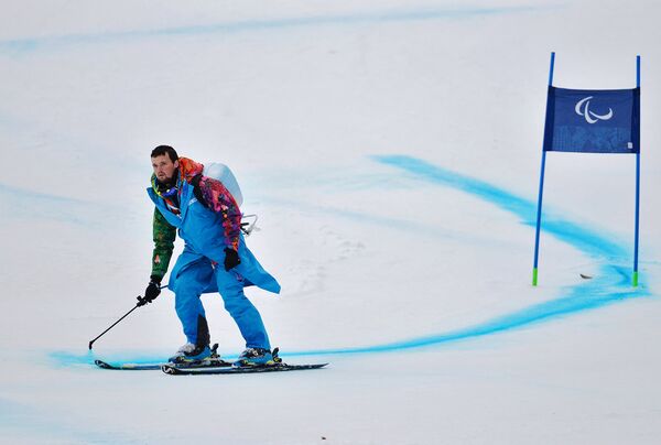 Волонтер обновляет разметку трассы на соревнованиях по горнолыжному спорту среди женщин на зимних Паралимпийских играх в Сочи
