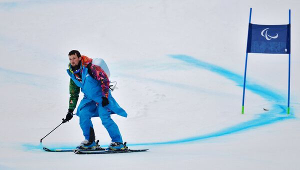 Волонтер обновляет разметку трассы на соревнованиях по горнолыжному спорту среди женщин на зимних Паралимпийских играх в Сочи
