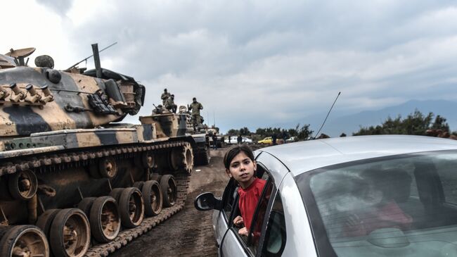 Турецкая девочка выглядывает из окна автомобиля во время стягивания войск турецкой армии к границе с Сирией