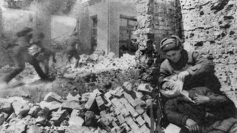 Сталинград. Декабрь 1942 г. Уличный бой. Санитарка перевязывает раненого