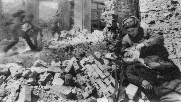 Сталинград. Декабрь 1942 г. Уличный бой. Санитарка перевязывает раненого. Архивное фото