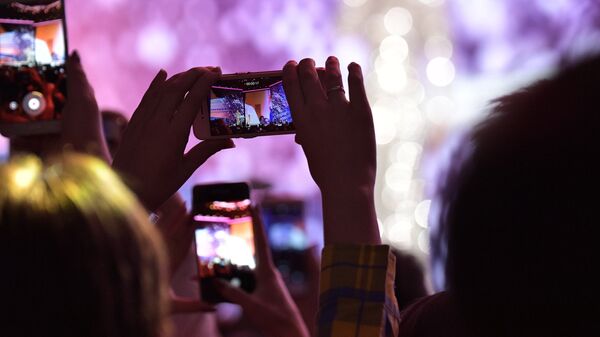 Запись видео на камеру мобильного телефона во время концерта. Архивное фото