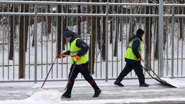 Дворники убирают снег с платформы одной из железнодорожных станций