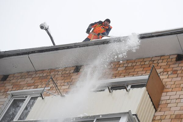 Сотрудник коммунальной службы во время чистки кровли от снега в Москве