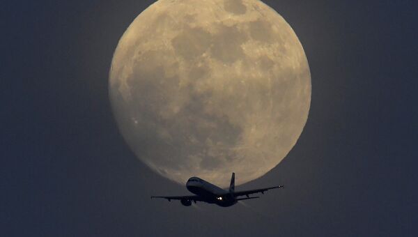 Самолет на фоне полной луны в небе над Лондоном, Великобритания