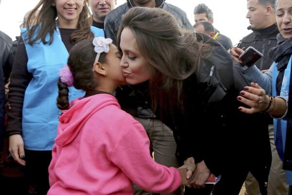 Посол доброй воли ООН и актриса Анджелина Джоли целует сирийскую девочку во время своего визита в лагерь беженцев Заатари в Иордании