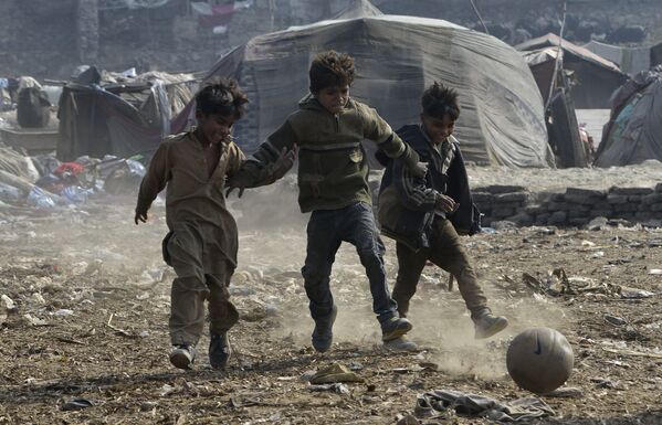 Пакистанские дети играют в футбол в трущобах в Лахоре. 30 января 2018 года