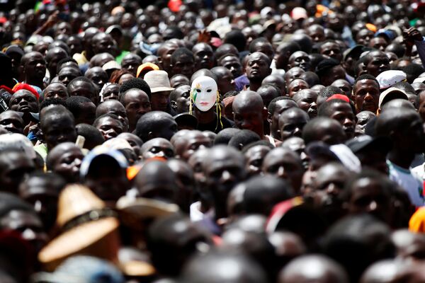 Человек в маске среди сторонников лидера оппозиции Кении Рейла Одинга во время его символической президентской присяги в Найроби, Кения. 30 января 2018 года