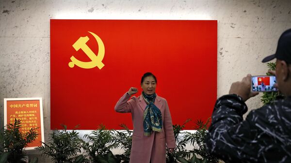 Женщина фотографируется у флага Коммунистической партии Китая в Шанхае