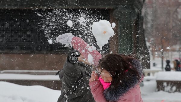Молодые люди играют в снежки на Манежной площади в Москве