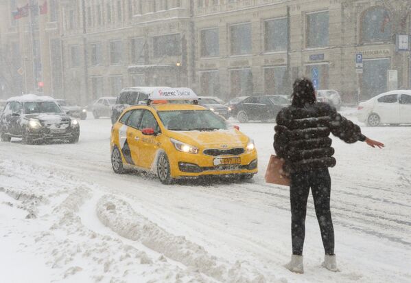 Девушка ловит такси на Тверской улице во время снегопада. 4 февраля 2018
