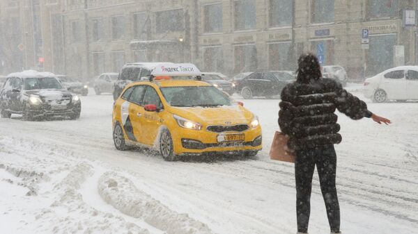 Девушка ловит такси на Тверской улице во время снегопада