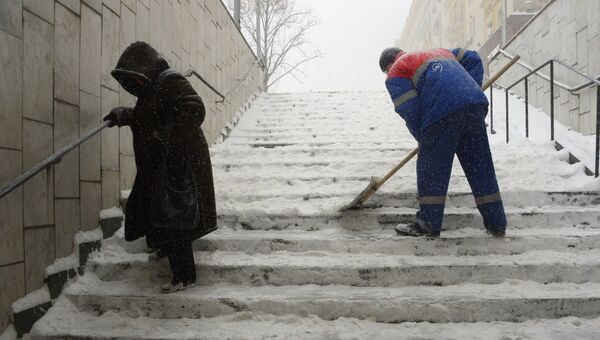 Сотрудник коммунальных служб убирает снег с лестницы подземного перехода во время снегопада в Москве. 4 февраля 2018