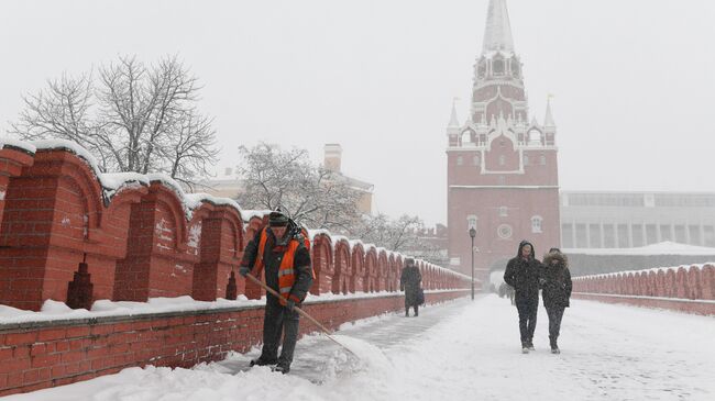 Сотрудник коммунальной службы чистит снег на мосту между Кутафьей и Троицкой башнями Московского Кремля во время снегопада