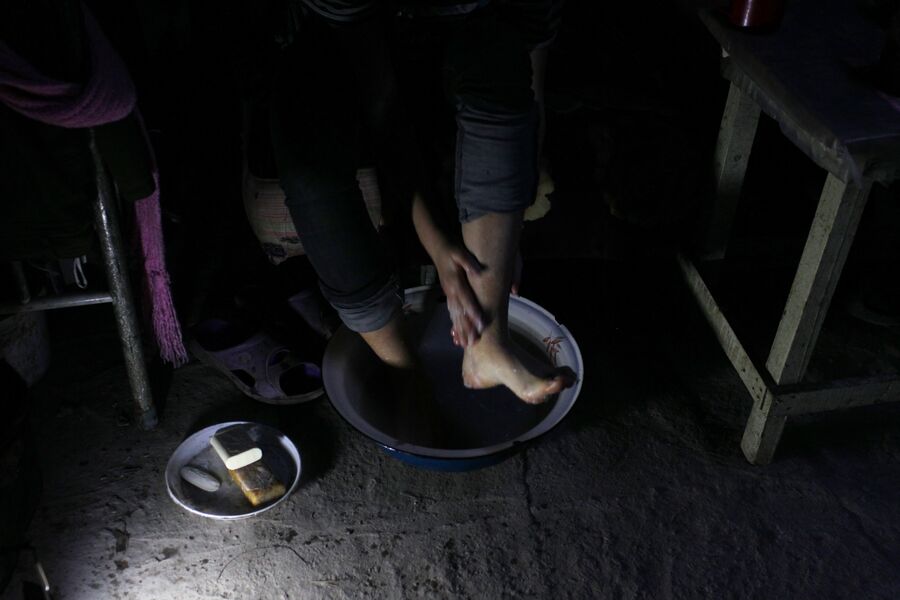 Марина моет ноги в подвале, где живет с семьей. Спартак, Донецкая народная республика