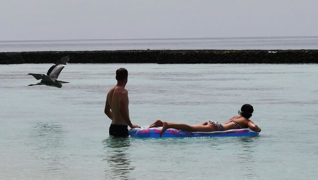 Туристы купаются в море у берега одного из Мальдивских островов