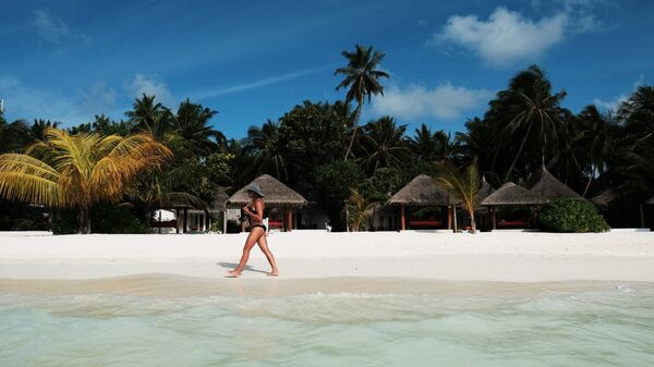Девушка идет по пляжу одного из Мальдивских островов