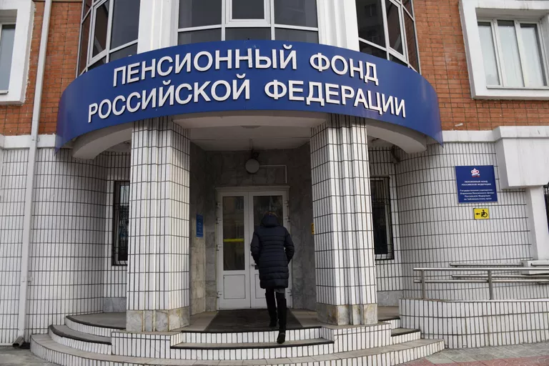 Женщина заходит в здание отделения Пенсионного фонда Российской Федерации Женщина заходит в здание отделения Пенсионного фонда Российской Федерации