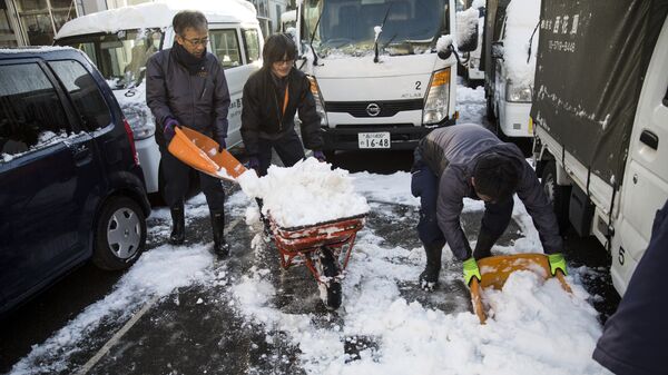 Служащие очищают стоянку от снега в районе Мегуро в Токио. Архивное фото