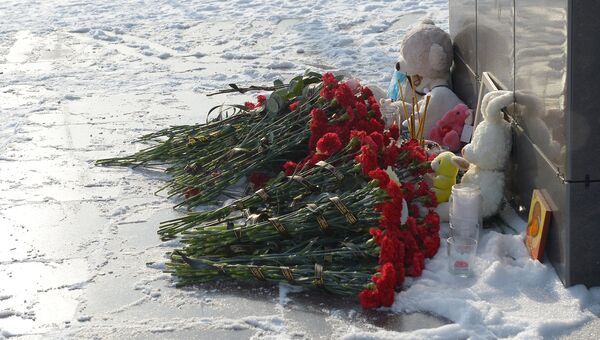 Цветы, свечи и детские игрушки фотографии самолета в центре Орска, принесенные в память о крушении Ан-148 Саратовских авиалиний. Архивное фото