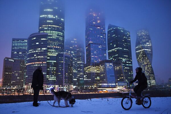 Прохожие гуляют на набережной Тараса Шевченко в Москве. На втором плане - Международный деловой центр Москва-Сити