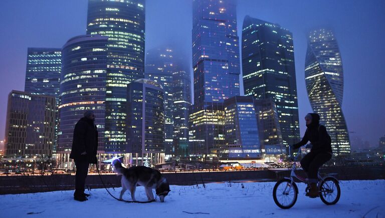 Прохожие гуляют на набережной Тараса Шевченко в Москве. На втором плане - Международный деловой центр Москва-Сити