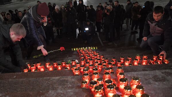 Люди зажигают свечи и кладут цветы на ступени Храма Христа Спасителя во время акции памяти о жертвах крушения самолета Ан-148 Саратовских авиалиний