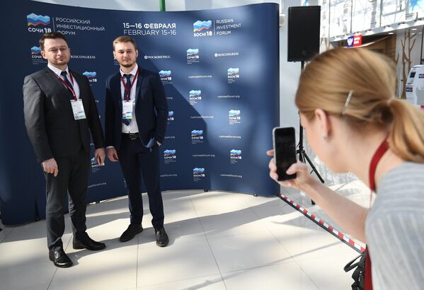 Участники Российского инвестиционного форума в Сочи фотографируются у баннера перед открытием