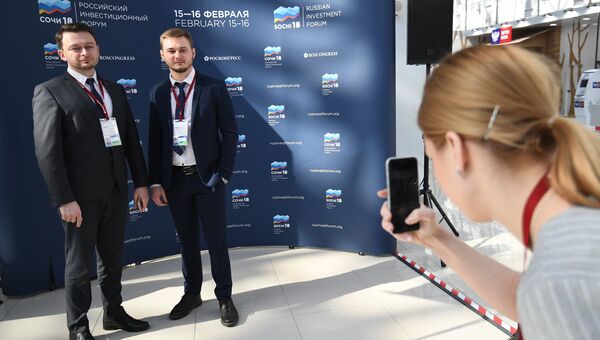 Участники Российского инвестиционного форума в Сочи фотографируются у баннера перед открытием