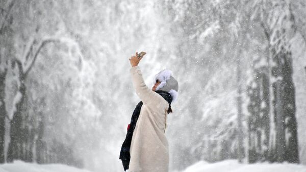 Девушка фотографируется на Воробьевых горах во время снегопада