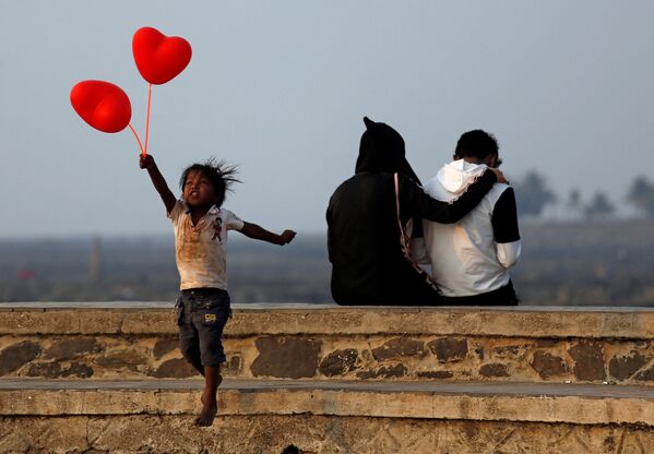 Ребенок на набережной продает воздушные шары  в День святого Валентина в Мумбаи