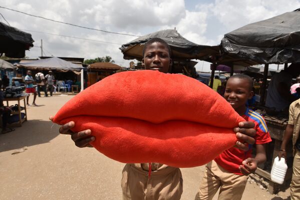 Мальчики позируют с подушкой в форме губ в День святого Валентина в пригороде Абиджана