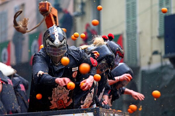 Участники ежегодной битвы апельсинами в Иврее, Италия