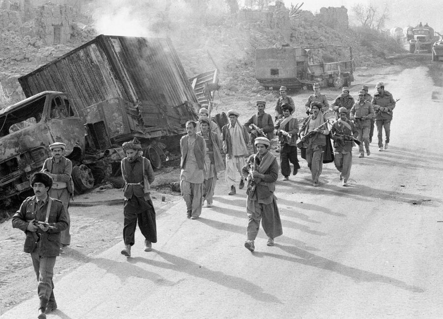 Бойцы народной милиции Афганистана и советские военнослужащие конвоируют захваченных в плен моджахедов. 1985 год