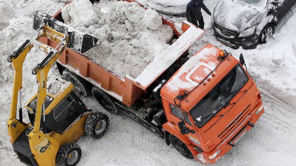 Погрузка снега в кузов грузового автомобиля на придомовой территории в Москве