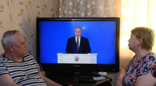 Мужчина с женщиной смотрят трансляцию ежегодного послания президента РФ Владимира Путина к Федеральному собранию. 1 марта 2018