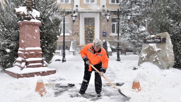 Мужчина убирает снег на одной из улиц в Симферополе