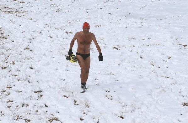 Мужчина идет по заснеженному пляжу Биарриц после купания в Атлантическом океане