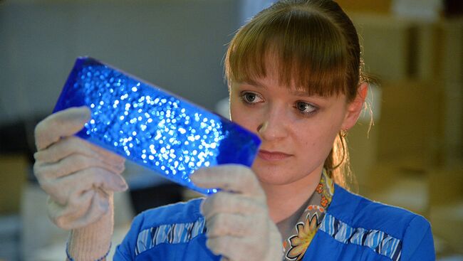 Сотрудница завода проверяет качество изготовленных кристаллов на Южноуральском заводе ОАО Кристалл в Челябинской области