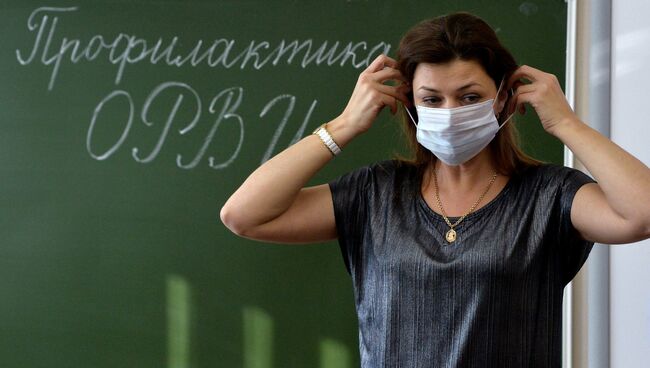 Учительница начальных классов гимназии № 96 в Челябинске объясняет ученикам правила использования медицинских масок в целях профилактики гриппа ОРВИ