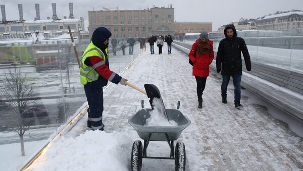 Сотрудник коммунальных служб во время уборки последствий снегопада на Парящем мосту парка Зарядье в Москве. Архивное фото